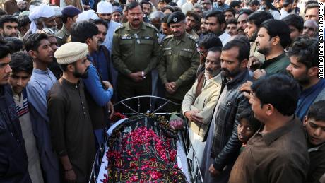 Le persone stanno accanto al corpo di un uomo che, secondo la polizia, è stato giustiziato sommariamente da una folla, nel villaggio di Tulamba, nel Pakistan centrale, il 13 febbraio 2022.