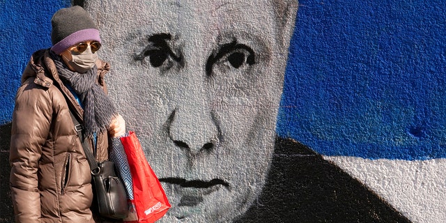 Una donna passa davanti a un murale raffigurante il presidente russo Vladimir Putin a Belgrado, in Serbia, sabato 12 marzo 2022. 