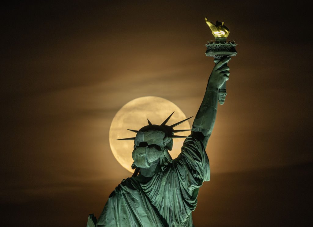 La luna piena splende dietro la testa della Statua della Libertà, facendola sembrare un'aureola.