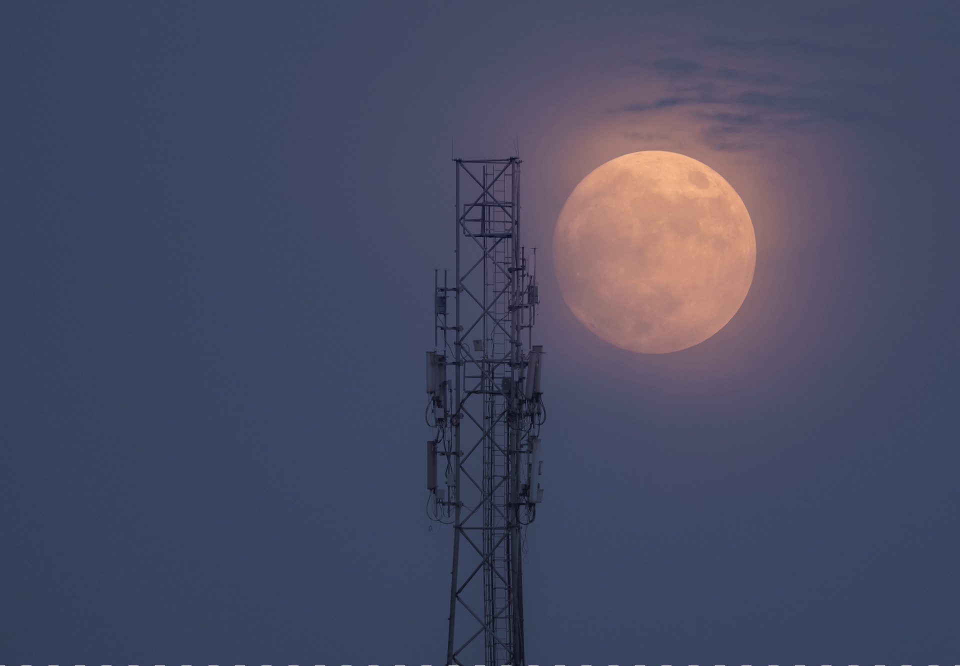 Una gigantesca luna blu brilla di un nebbioso arancione accanto alla torre.