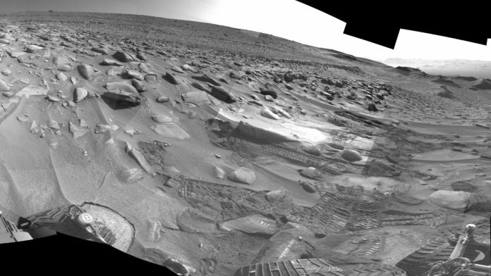 black and white view of a martian landscape littered with sand dunes and large rocks