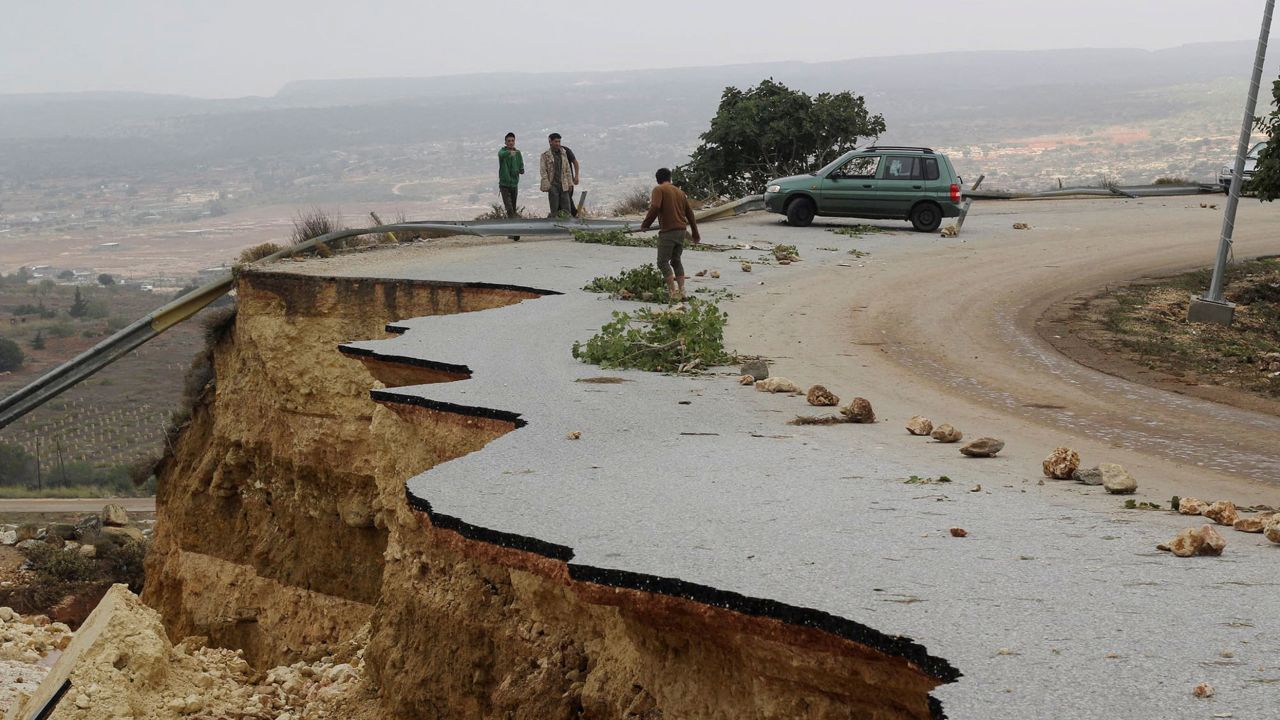 Persone ferme su una strada danneggiata quando una forte tempesta e una forte pioggia hanno colpito la città di Shahat, in Libia, l'11 settembre 2023. 